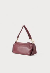 Sac à main en cuir bordeaux avec une forme structurée, une poignée courte, des garnitures en or et une texture lisse. Fermeture par zip sur le dessus.