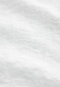 Tissu blanc présentant une surface douce et texturée avec des plis subtils, indiquant un matériau léger et respirant.