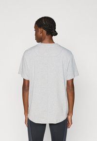 Ανοιχτό γκρι κοντομάνικο μπλουζάκι από μαλακό ύφασμα, με χαλαρή εφαρμογή, στρογγυλή λαιμόκοψη και ελαφρώς κυρτή ραφή. Ελάχιστες ραφές ορατές.