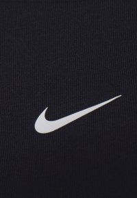 Mustapohjainen ribbikangas, jossa on valkoinen Nike-swoosh-logo keskitettynä alareunaan. Rakenne on sileä ja siinä on tasaiset pystysuorat raidat.