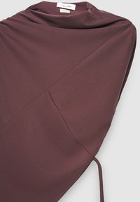 Haut en tissu mauve avec un design drapé, des liens latéraux et une silhouette décontractée. Confectionné dans un matériau lisse et léger avec des détails de couture minimaux.