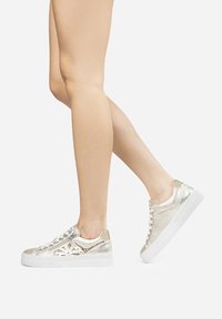 Sølvmetalliske sneakers med teksturerede accenter, hvid gummisål og dekorative elementer. Glat og skinnende finish med snørelukning.