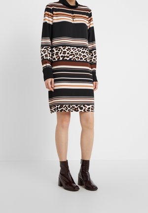 Schwarzes Kleid mit horizontalen Streifen in Braun, Beige und Creme, ausgestattet mit einem gepunkteten Saum im Leopardenmuster. Lange Ärmel und Kragen-Detail.