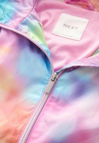 Lekka, pastelowa kurtka zapinana na zamek z gładką, błyszczącą teksturą. Posiada srebrny zamek błyskawiczny oraz różową etykietę wewnętrzną "NEXT."