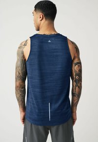 Granatowy bezrękawnik sportowy z teksturowanym wzorem i odblaskowym akcentem z tyłu. Materiał wydaje się lekki i oddychający.