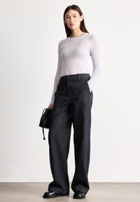 Svetlo siva rebrasta majica z dolgimi rokavi, kombinirana s temno modrimi kavbojkami širokih nogavic. Črno torbico z zategovalnim trakom in črni čevlji dopolnjujejo videz.