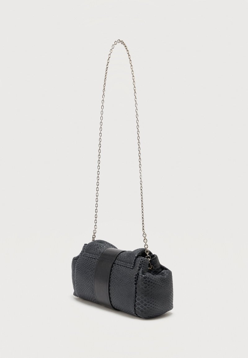 Pochette noire texturée avec une large bande noire et une fine anse chaîne argentée, présentée sur un fond blanc uni.