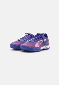 Puma atletske cipele s gornjim dijelom od mrežaste tkanine u ljubičastoj i ružičastoj boji s plavim akcentima, teksturiranom potplatom i kontrastnim bijelim detaljima s logom.