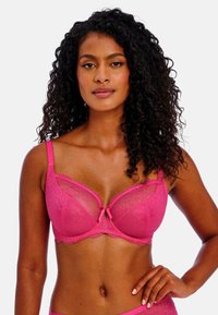 Sostenedor de encaje rosa con varillas, paneles translúcidos y borde festoneado. Acento de moño en el centro. Tirantes ajustables y textura suave.