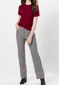 Haut bourgogne à manches courtes avec détail plissé associé à un pantalon noir et blanc à motif pied-de-poule ajusté. Modèle portant des bottines noires.