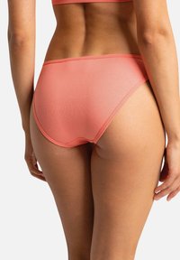 Bas de bikini côtelé pêche avec une coupe taille haute et une texture lisse, présentant une coupe sans couture autour des jambes et de la taille.