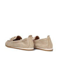 Beige suède instappers met een ronde neus, een decoratieve strik aan de voorkant en een witte rubberen zool. Gela naturelle afwerking en minimale accenten.