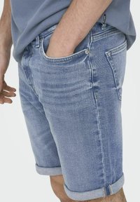 Shorts de mezclilla azul claro con dobladillos enrollados, que cuentan con un bolsillo frontal y un ligero desvanecimiento en la tela para un look casual.