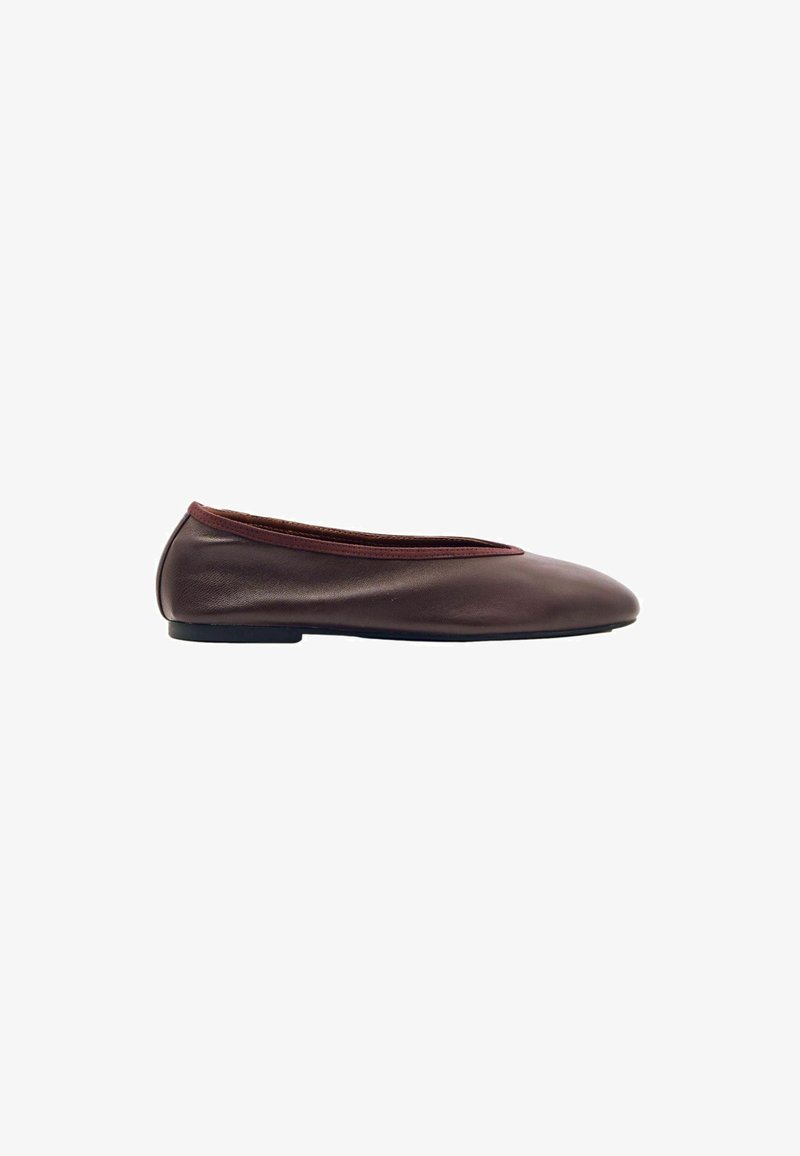 Zapato plano de cuero marrón con punta redondeada, tacón ligero y ribete cosido a lo largo de la abertura, visto de lado sobre fondo blanco.