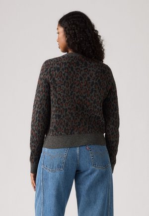 Gray knitted sweater with an orange and black leopard print, featuring a rounded neckline and ribbed hem, paired with blue wide-leg jeans.