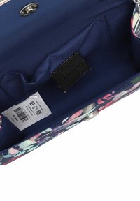 Kukkakuosinen kangaslaukku, jossa on laivastonsininen vuori, sisätasku ja musta merkki. Metallinen nepparikiinnitys näkyvissä.