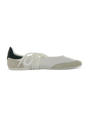 Witte en beige platte sneaker met zwart hiel detail en lange witte veters gewikkeld rond de middenvoet op een witte achtergrond.