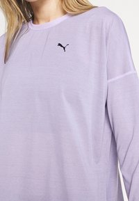 Purple long-sleeve shirt made of soft fabric. Features a contrasting light purple collar and a small black logo on the chest.