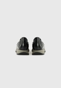 Black patent leather shoes with a smooth texture, low gray rubber sole, and minimal detailing. Rounded back and sleek silhouette.