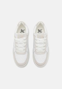 Hvite sneakers med beige detaljer, perforert tåboks, flate skolisser og polstret krage. Den indre fôringen er lyse farger med logodetalj.