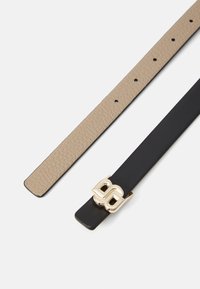 Deux ceintures : l'une en cuir beige texturé avec des trous, l'autre en cuir noir uni avec une boucle en or en forme de double B.