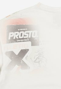 Biała koszulka z krótkim rękawem z wyraźnym nadrukiem graficznym z napisem "PROSTO" oraz różnymi kształtami w kolorze czarnym, czerwonym i szarym. Gładka faktura.