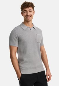 Grau gestricktes Polohemd mit kurzen Ärmeln, einer gerippten Textur, einem Kragen und einer linken Brusttasche. Der Saum ist mit einem gerippten Muster abgeschlossen.