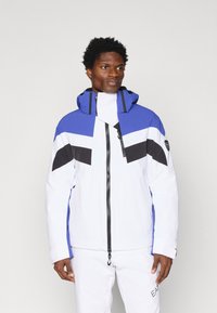 Meeste jope, mis on valmistatud veekindlast materjalist, sinise, valge ja musta värviblokiga disainiga, kõrge kraega ja esise luku sulgemisega.