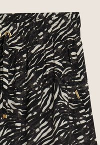 Falda con estampado de cebra en blanco y negro, con una cintura elástica fruncida, cordón ajustable y una pequeña etiqueta dorada como detalle en el lateral.