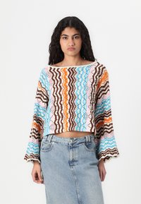 Virkat crop-top med flerfärgade vågiga mönster i blått, orange, rosa och brunt; långa utsvängda ärmar och en bred halsringning.