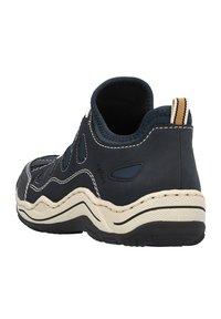 Mörkblå sneakers med texturerad ovandel, beige sula och vita sömmar. Har utskurna mönster och en randig dragflik vid hälen.