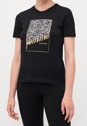 Kobieta nosząca czarny t-shirt z kwadratem w panterkę i złotym napisem z tekstem "femme" oraz "FUTURE" z przodu.
