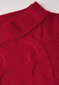 Maglione rosso lavorato a maglia con colletto a coste e motivo testurizzato, che mette in evidenza una consistenza morbida e pelosa e un aspetto accogliente e caldo.