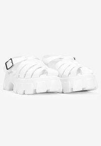 Las sandalias de goma blancas presentan un diseño de correas entrelazadas, punta abierta, hebilla ajustable y suela gruesa con surcos definidos.
