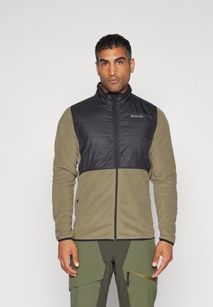 Chaqueta negra y verde oliva con sección superior acolchada, inferior de forro polar, cierre de cremallera y cuello alzado. Color sólido sin patrones.