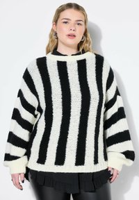 Maglione a righe bianco e nero in maglia con scollatura ampia, vestibilità oversize e maniche lunghe. La trama è morbida, con polsini e orlo a coste.