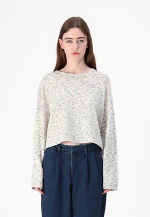 Maglione corto crema con un motivo testurizzato, maniche lunghe e scollo ampio, abbinato a pantaloni blu scuro a vita alta.