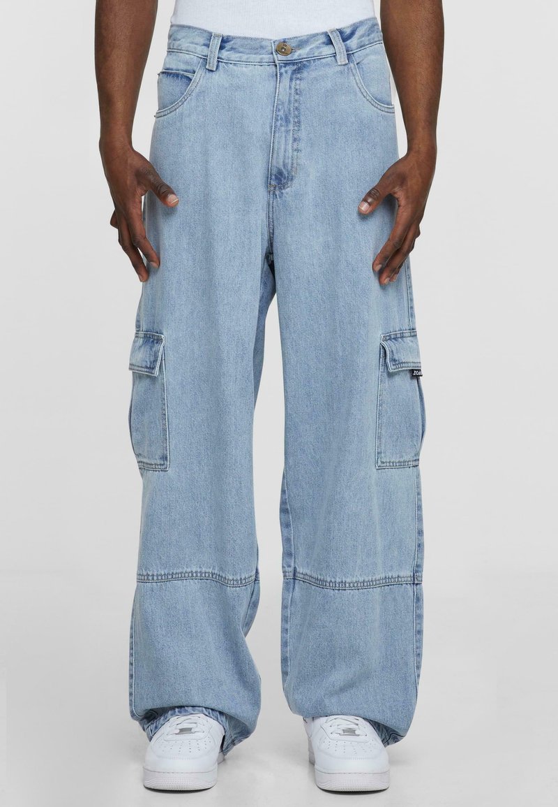Lys blå denim cargo bukser med løs passform, som har flere lommer og synlige sømdetaljer. Kombinert med hvite sneakers.