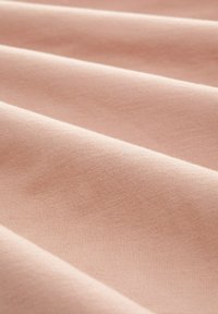 Světle růžová látka s hladkým povrchem, která má jemné žebrování a mírné záhyby. Materiál vypadá měkce a pružně.