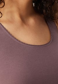 Paarse tanktop met een ronde halslijn en een delicate gestikte afwerking. De stof heeft een gladde textuur en een aansluitend ontwerp.