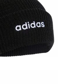 Gorro de punto negro con textura acanalada y un logotipo bordado en blanco de "adidas" en la parte frontal.