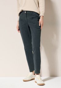 Dark gray cotton chinos with a straight leg, front pockets, and a button closure. Paired with light-colored athletic shoes.