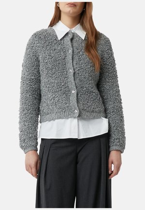 Grauer gestrickter Cardigan mit einer flauschigen Textur, rundem Ausschnitt und Knopfverschluss mit klaren Knöpfen. Getragen über einem weißen Hemd mit Kragen.