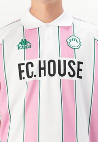 Biała koszulka polo z różowymi i zielonymi pionowymi paskami, z logo Kappa na lewej piersi oraz napisem "F.C. HOUSE" w pogrubionym czarnym kolorze.