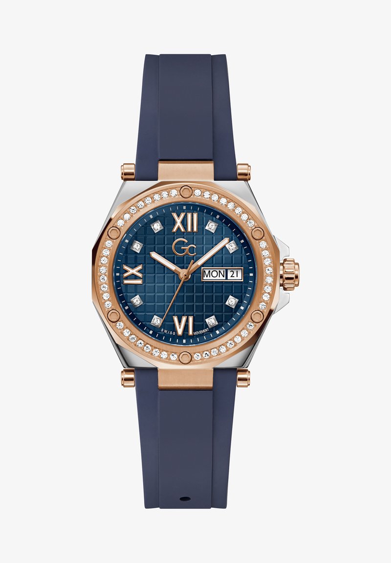 Aštuonkampis laikrodis su tamsiai mėlyna guma apyranke, rožuoto aukso akcentais, mėlynu tekstūruotu ciferblatu, kristaliniais valandų žymenimis ir datos rodymu.