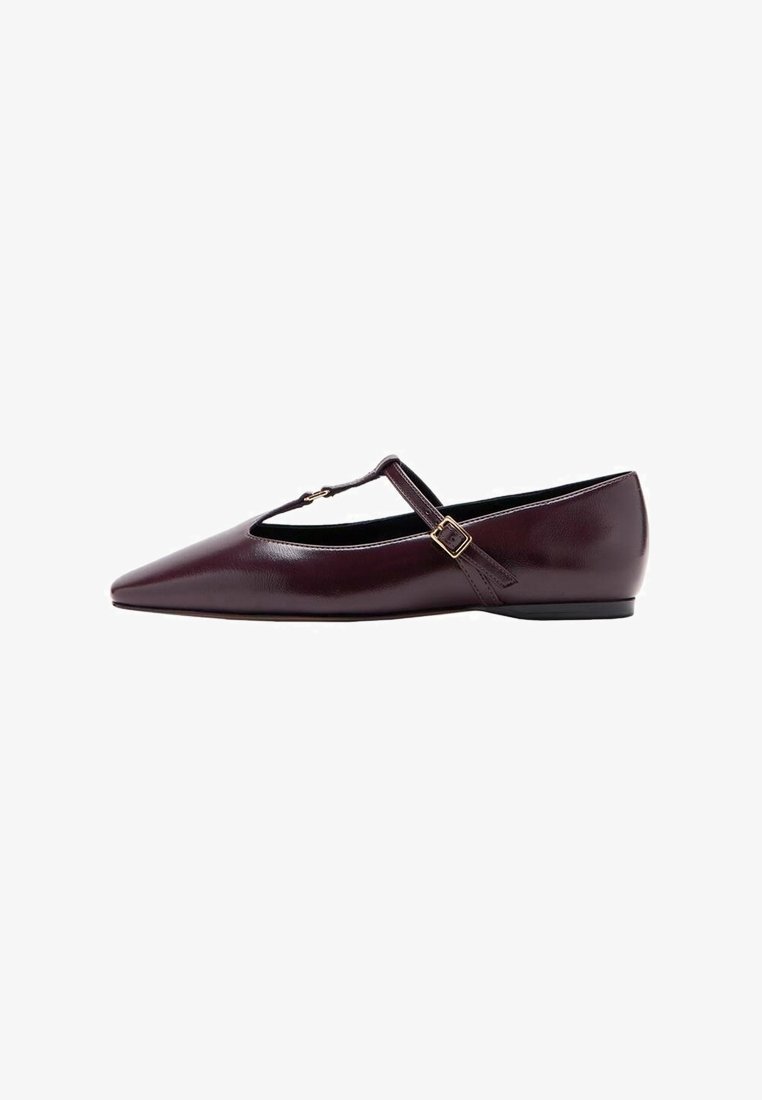 Chaussure plate pointue bordeaux foncé avec bride en T et boucle dorée sur fond blanc.