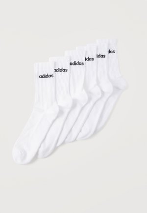 Έξι ζευγάρια λευκές κάλτσες κοντού μήκους με μαύρο λογότυπο "adidas" στα ριμπ μανσόνια, τοποθετημένα σε διάταξη ανοιχτού φεγγαριού σε απλό φόντο.