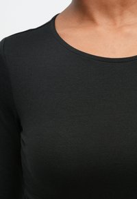 Svart langermet topp med rund hals, laget av glatt, elastisk stoff, med en ren finish og tettsittende design.