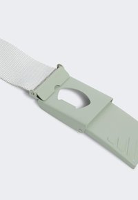 Jasnozielony plastikowy zamek z wyciętym wzorem, przymocowany do teksturowanego szarego paska. Posiada płaską końcówkę z ukośnymi rowkami.