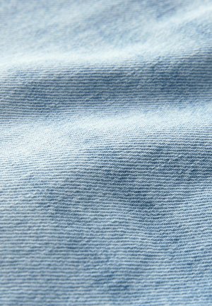 Tkanină de denim de culoare albastru deschis, cu o țesătură texturată, arătând variații subtile de culoare și având o senzație netedă și moale.